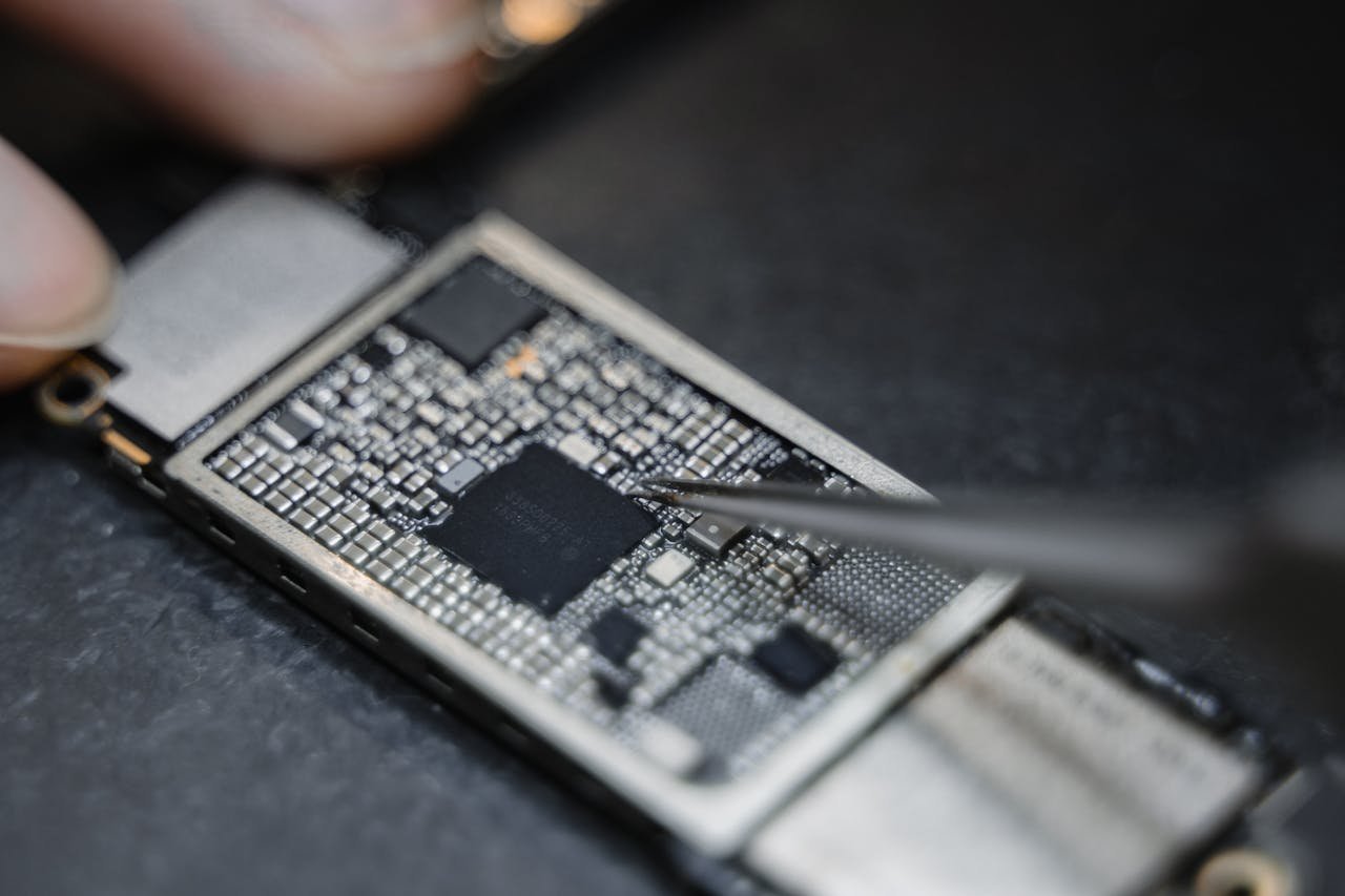 Technician performing precision board-level phone repair with tweezers
